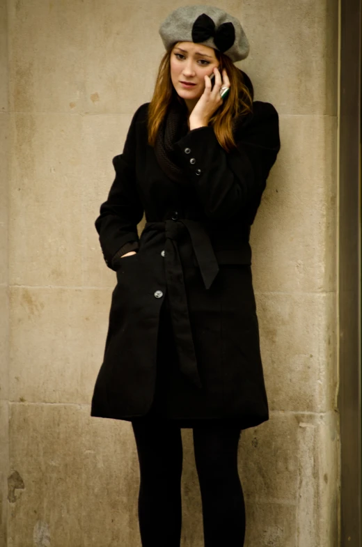 a woman in a coat and hat is talking on the phone