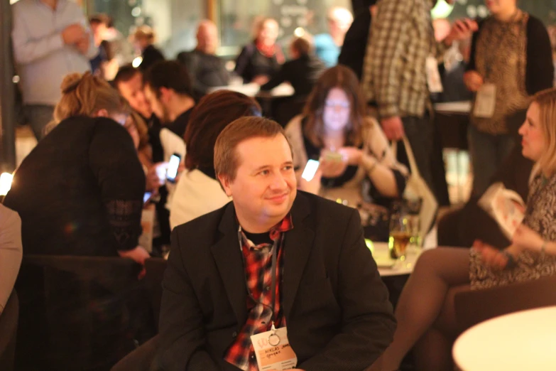 a young man sitting in a room full of people