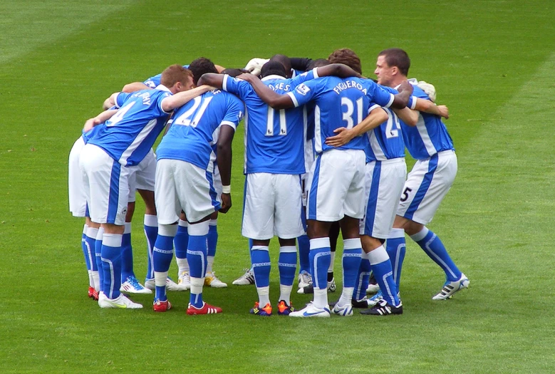 soccer players huddle together on the field