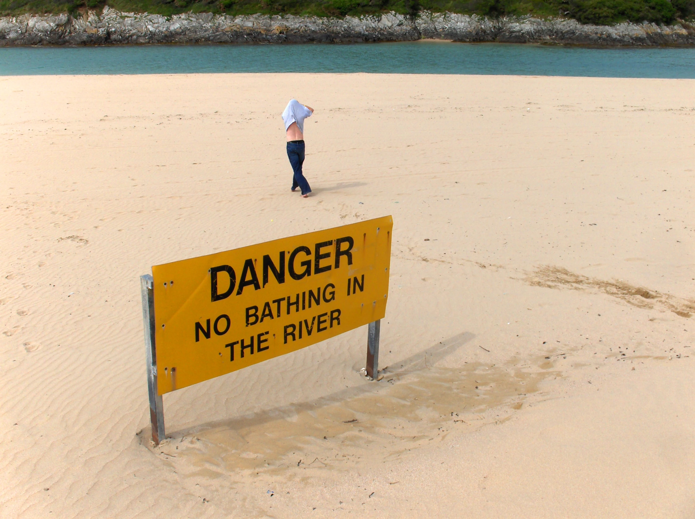 a person that is walking in sand with a sign