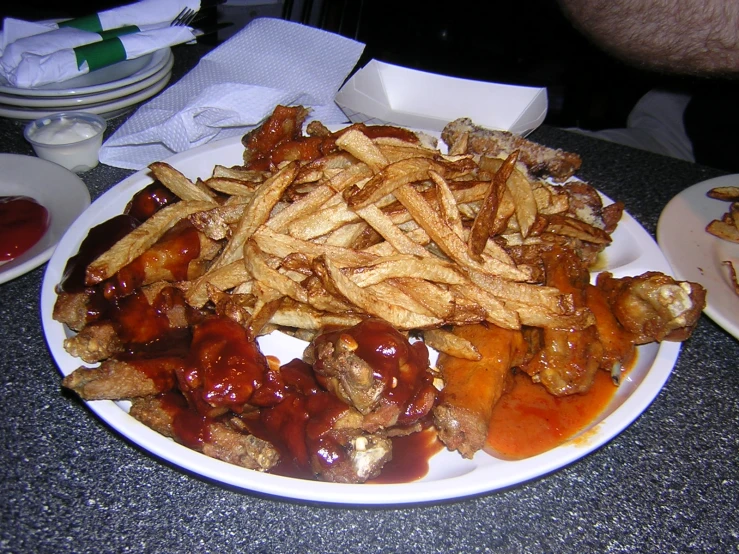 french fries are on a plate with meat covered in ketchup