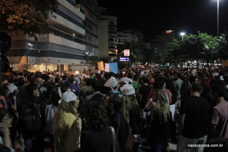 a crowd of people standing on a street near a building