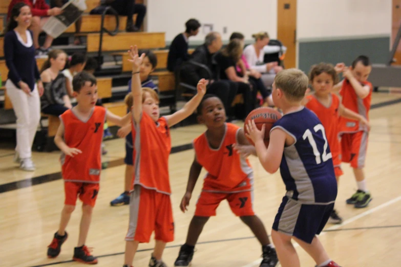 a group of s playing basketball inside of a gymnasium