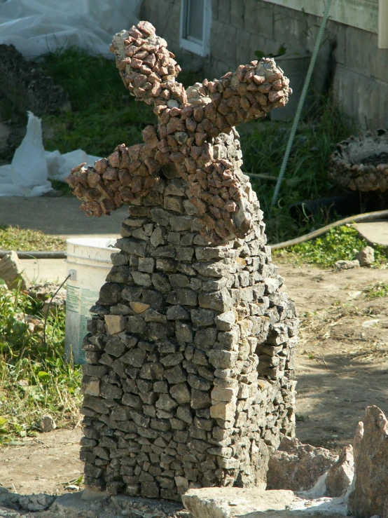 sculpture made out of bricks sitting next to grass and rocks
