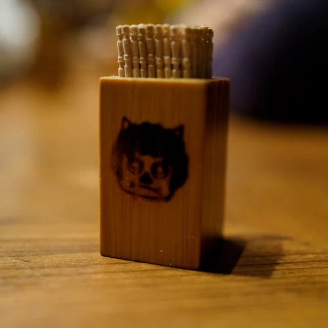 this is a small wooden lighter case with a face on it