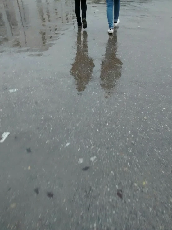 two people walking through the water carrying umbrellas