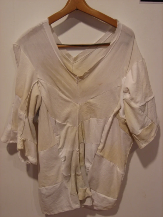 a white shirt hanging up on a wooden hanger