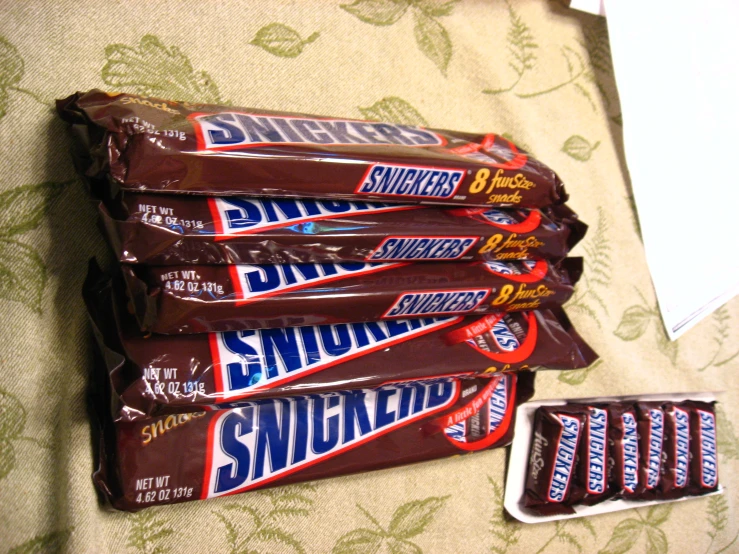 a pile of six bars of snickkers sitting on top of a bed