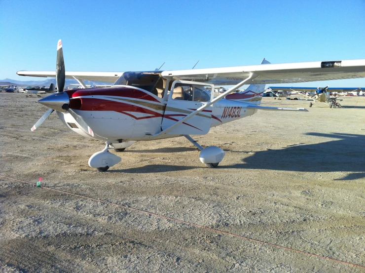 a small red and white airplane is on the ground