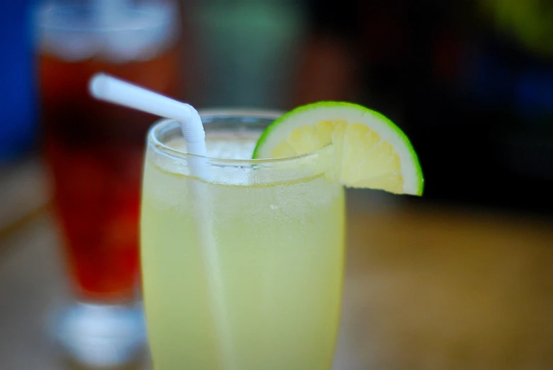 two glasses filled with yellow liquid, and one with a lime slice on top