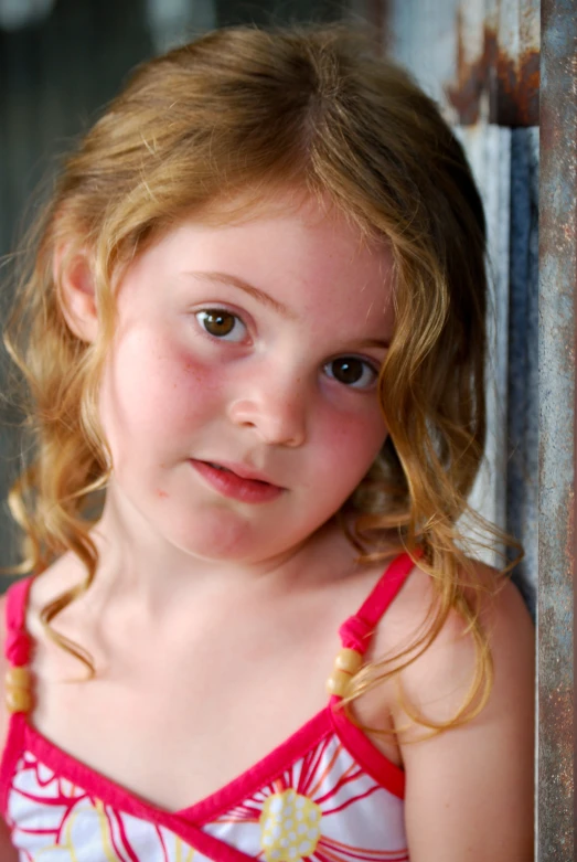 a little girl poses for a picture in front of a metal door