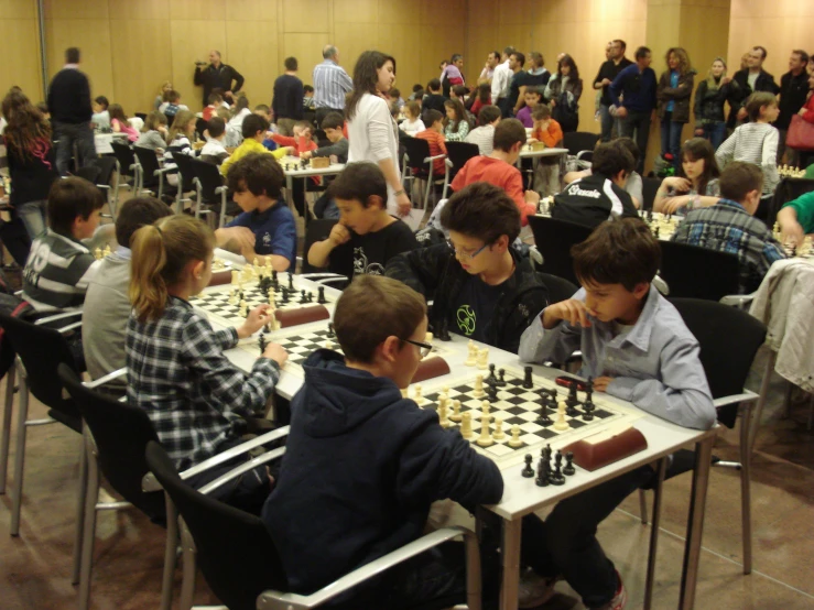 people playing chess in the middle of a room filled with tables