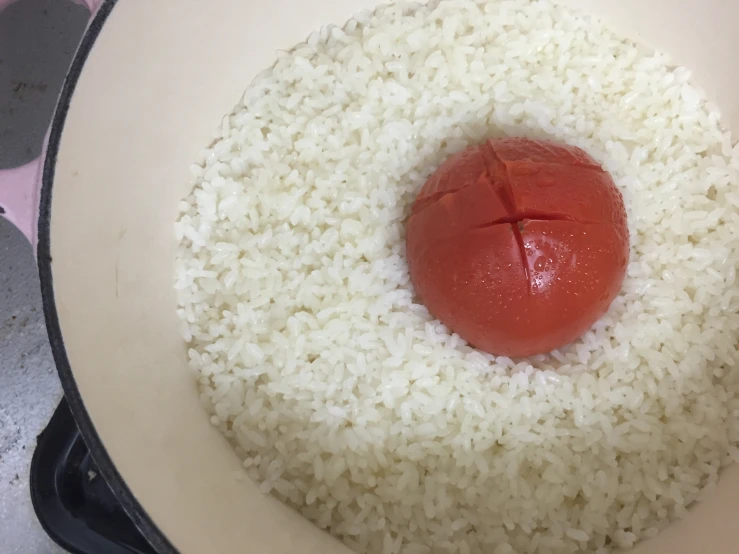 rice with a cherry tomato in it and cooking pot