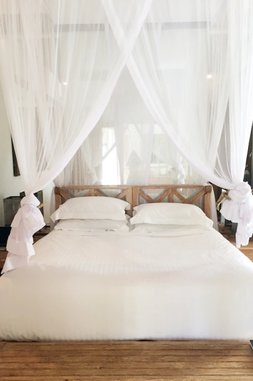 white bed covered with a sheered canopy with a remote