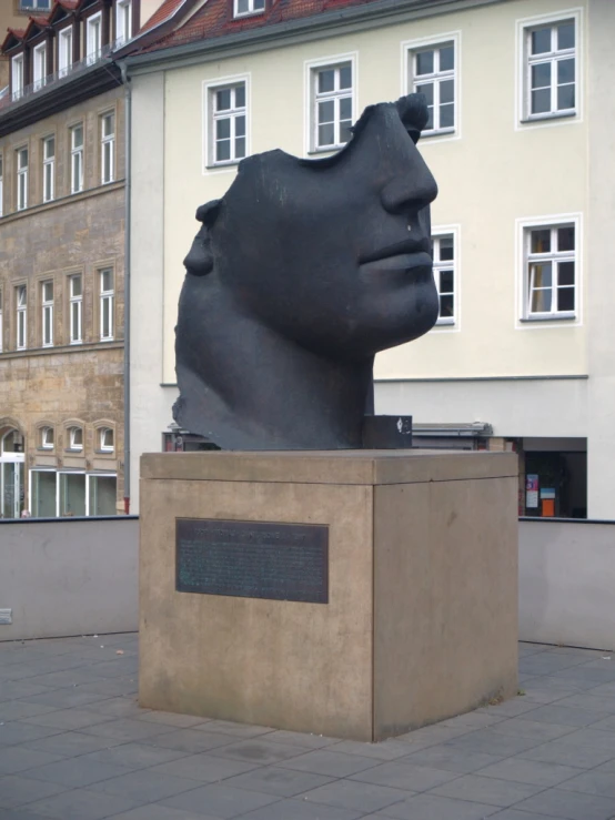 the head of a large statue sits behind a block