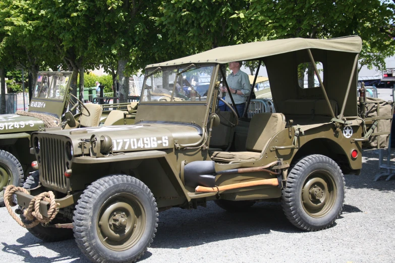 there are men standing near a military jeep