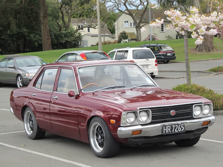 an older maroon car is parked on a parking lot