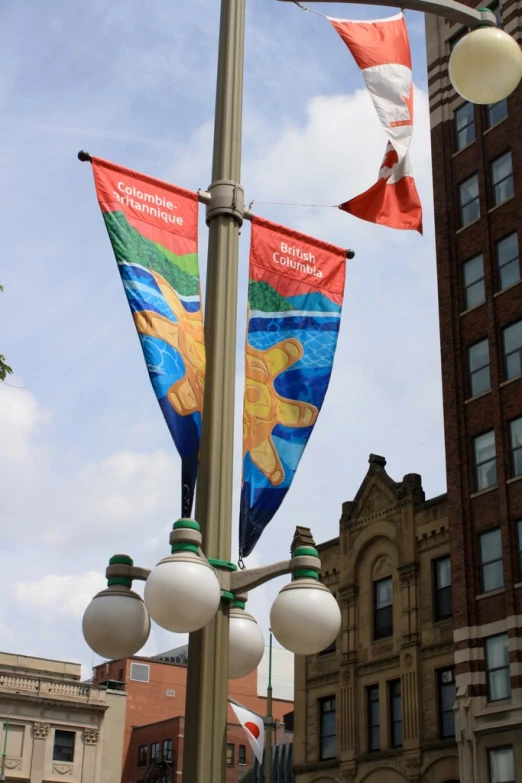 several flags on a street lamp next to a building