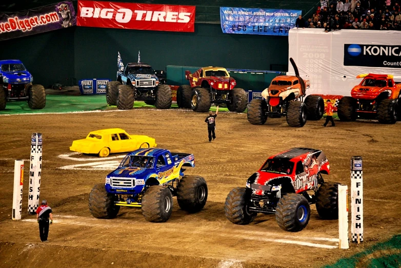 a number of monster trucks driving in a competition