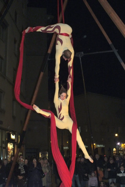 a performer hangs upside down on the rope at a circus