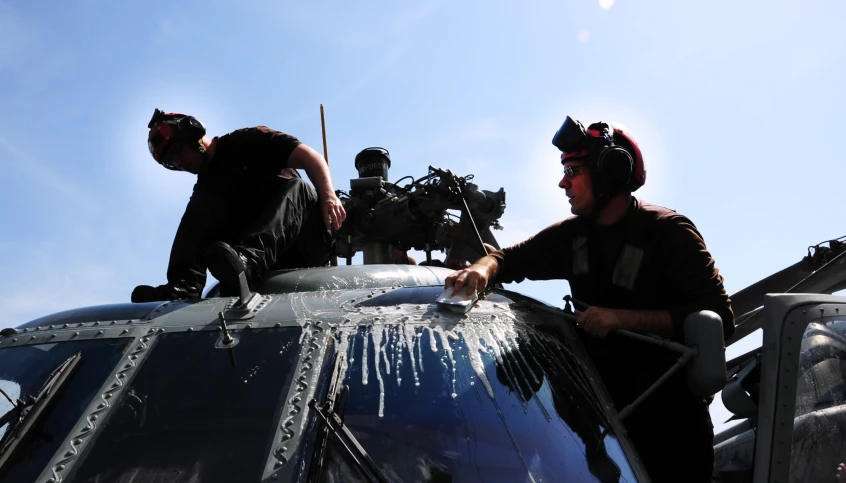 two men standing on top of a helicopter