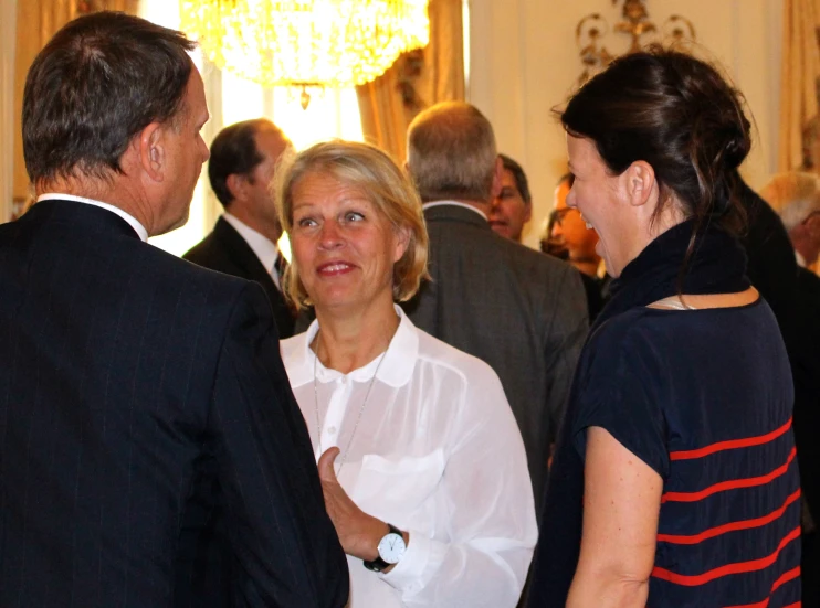 two woman in white shirts talk with two men in formal wear