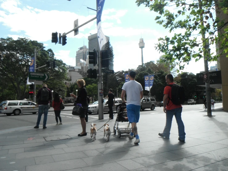 people walking on the street while one person hes their dog in a stroll