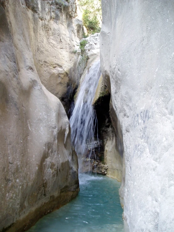 the cave is filled with blue pool water and water cascading down to the bottom