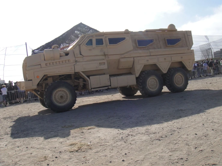 the large vehicle is on the dirt and people stand around