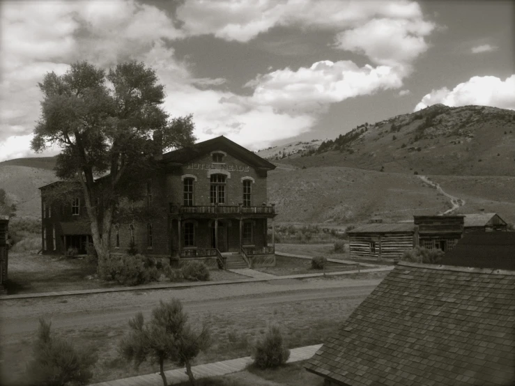 an old farmhouse building and trees are near the mountains