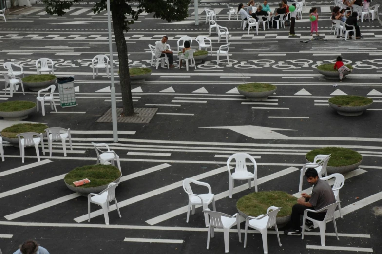 an empty road with chairs and a man sitting in one