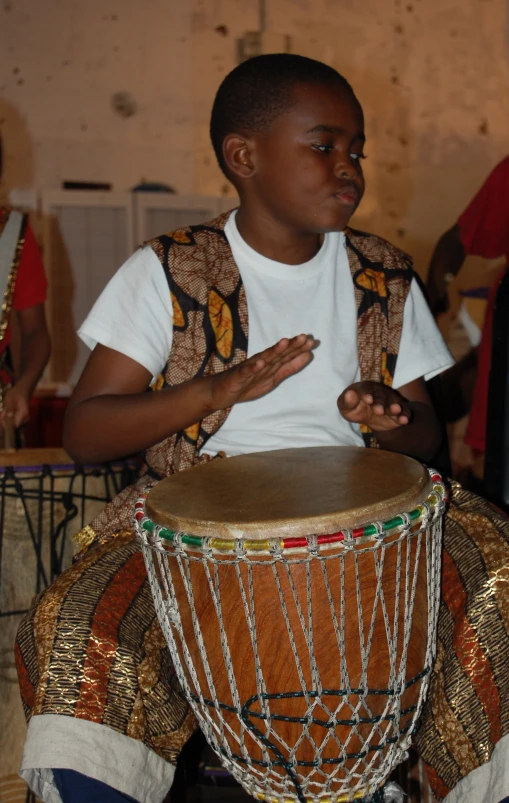 a boy sitting next to a wooden drum