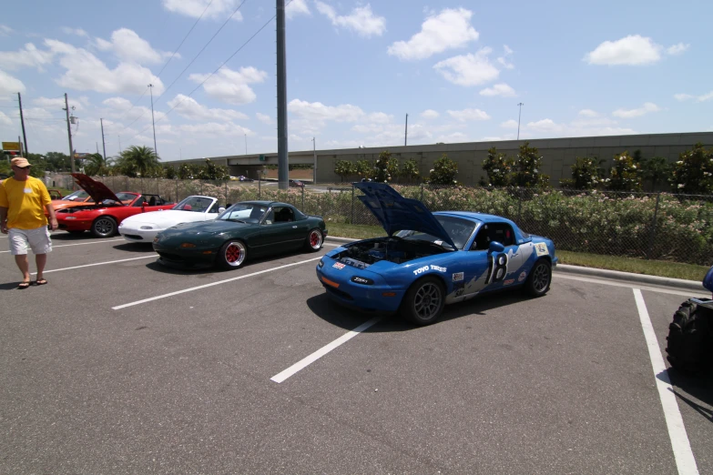 several sports cars parked in an open lot next to a building