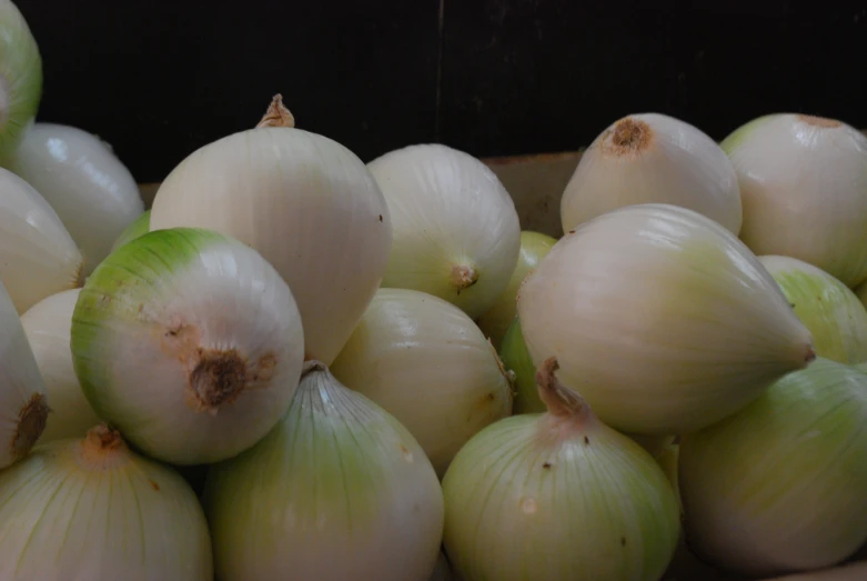 many onion bulbs are stacked together in an open bowl