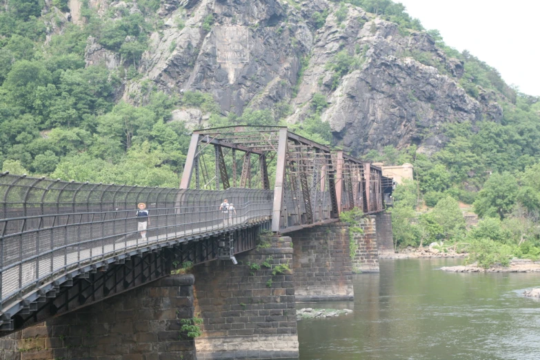 two people are on the old bridge that runs through a valley
