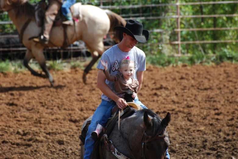 an older man holding a child riding on the back of a brown horse