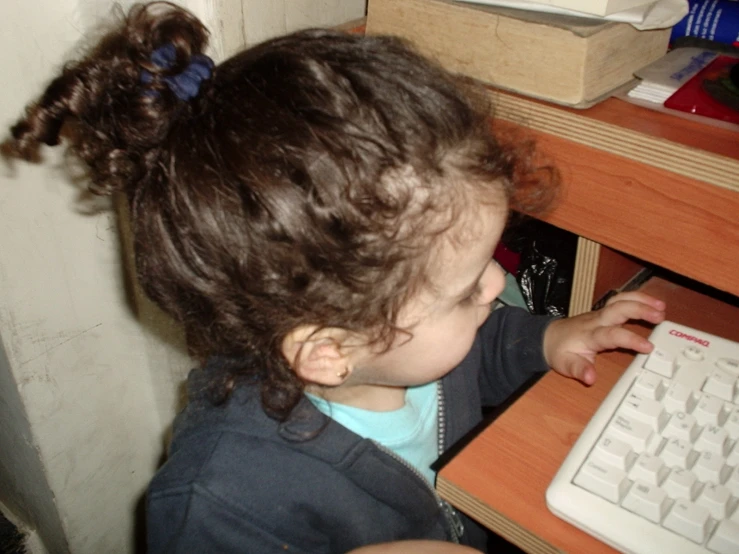 a little girl typing on a keyboard at a desk