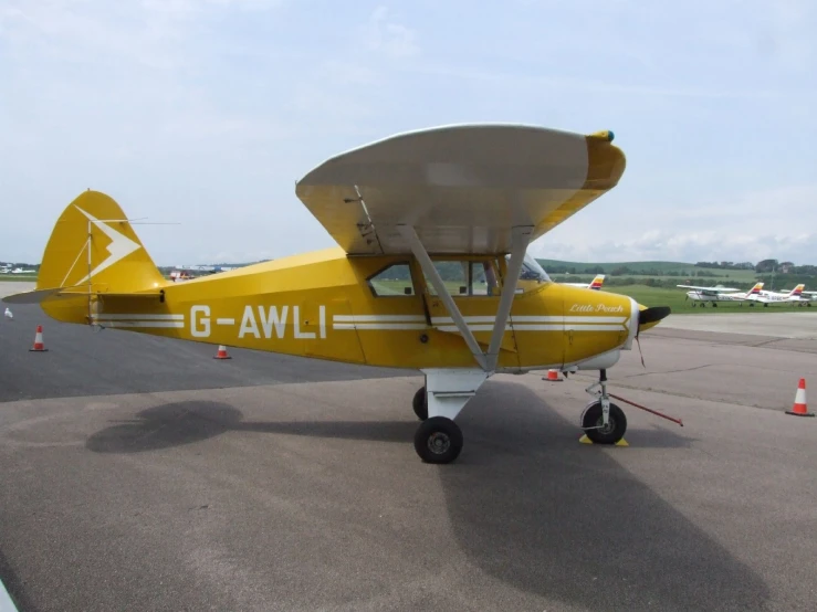 a small yellow airplane is sitting on a tarmac