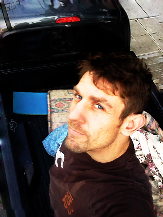 a man sitting at an open suitcase next to a car