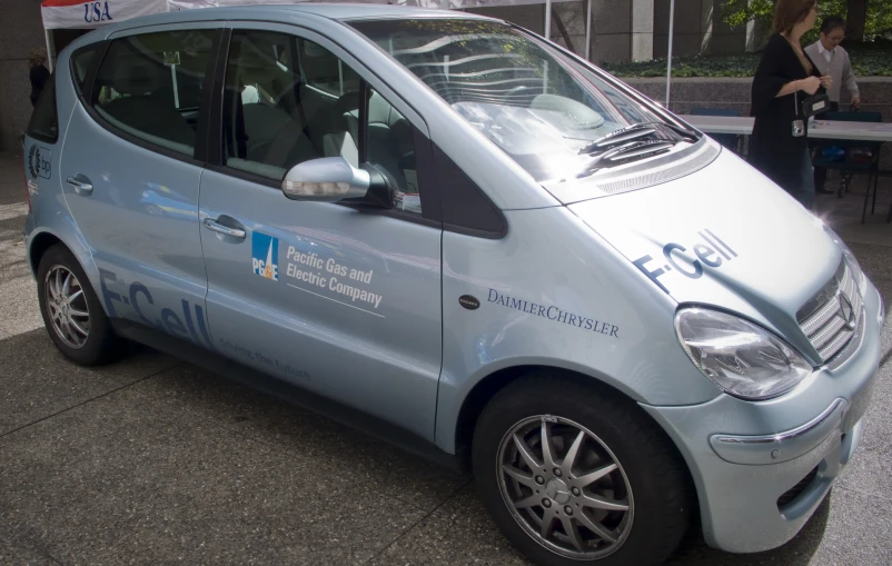 a small silver car with a sign on top of it