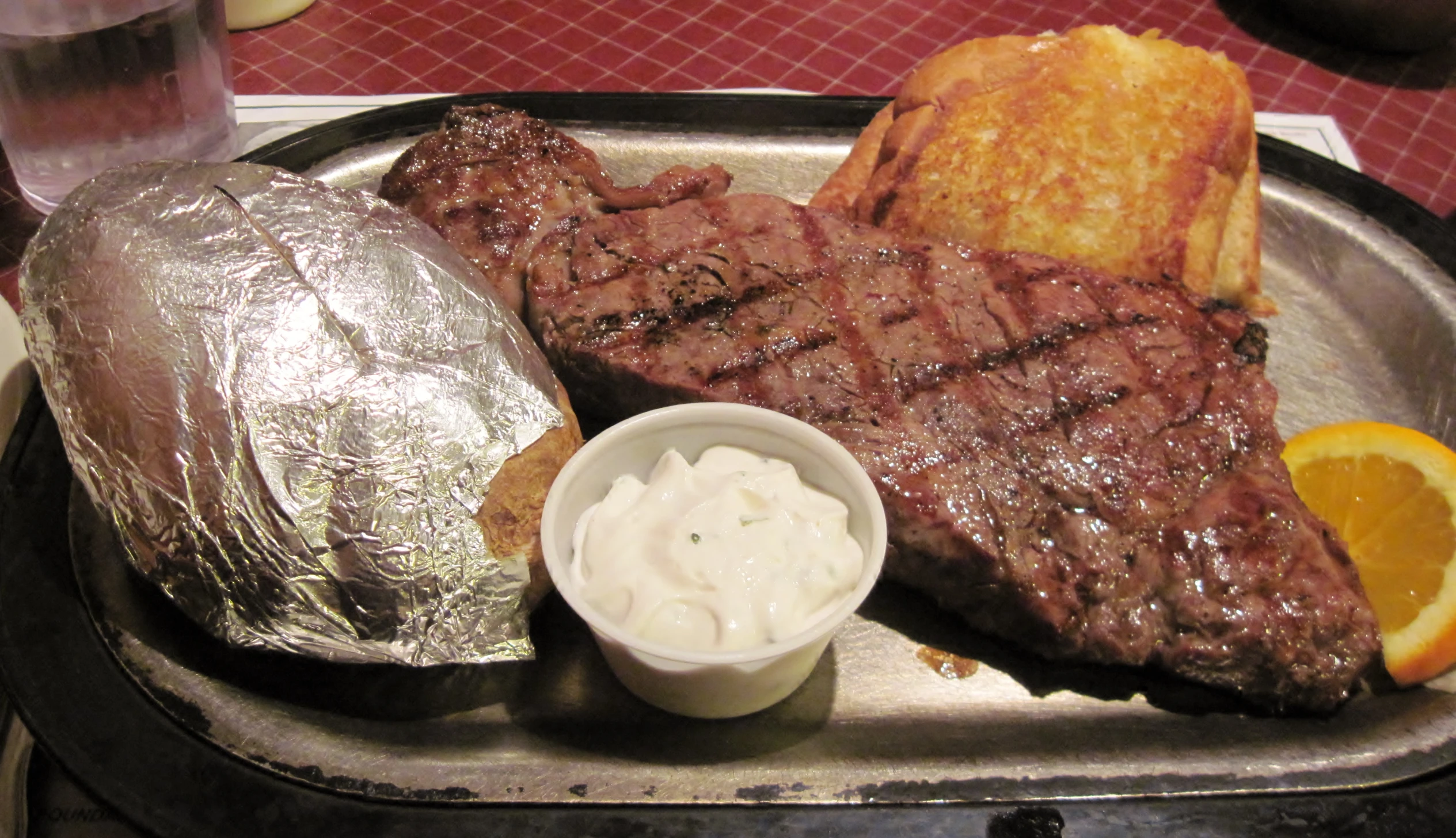 steak, grilled steak, and bread with sour cream on metal tray