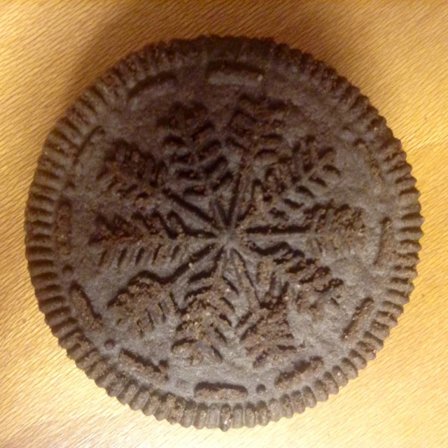 an old looking cookie with carvings and snowflakes on it