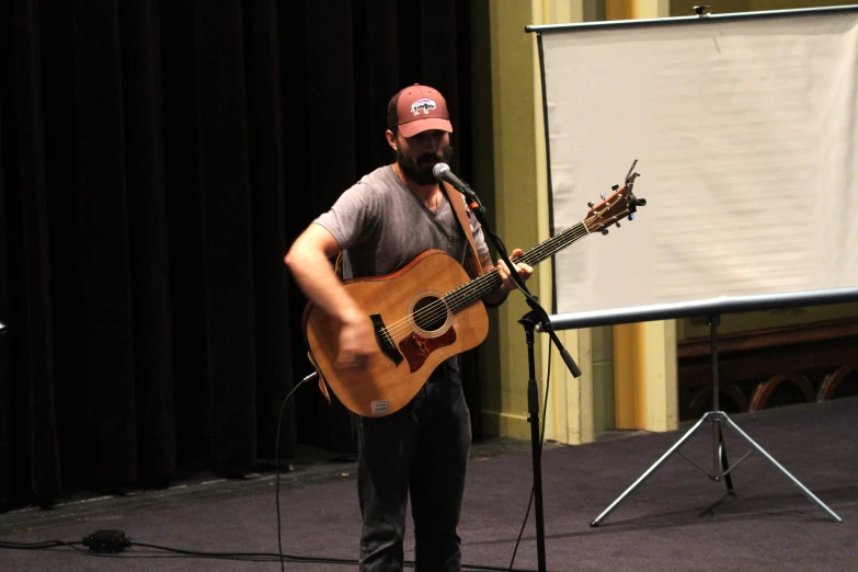 a man on stage singing with a guitar and microphone