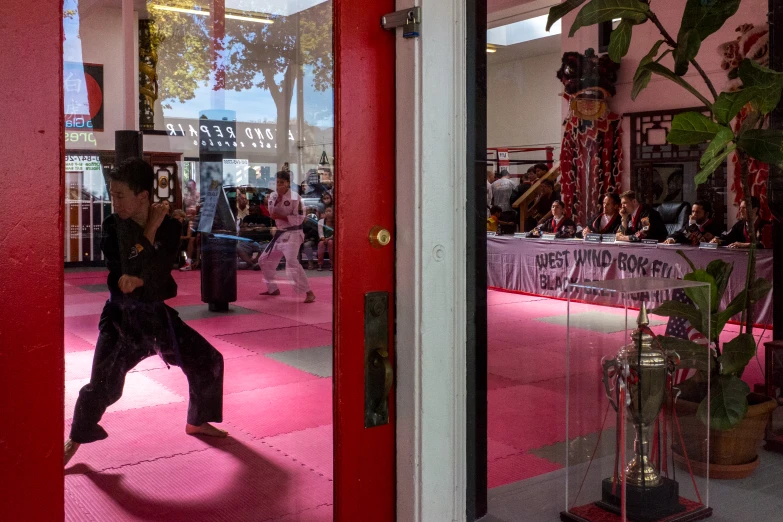 a boy performing some karate moves through the windows of a shop