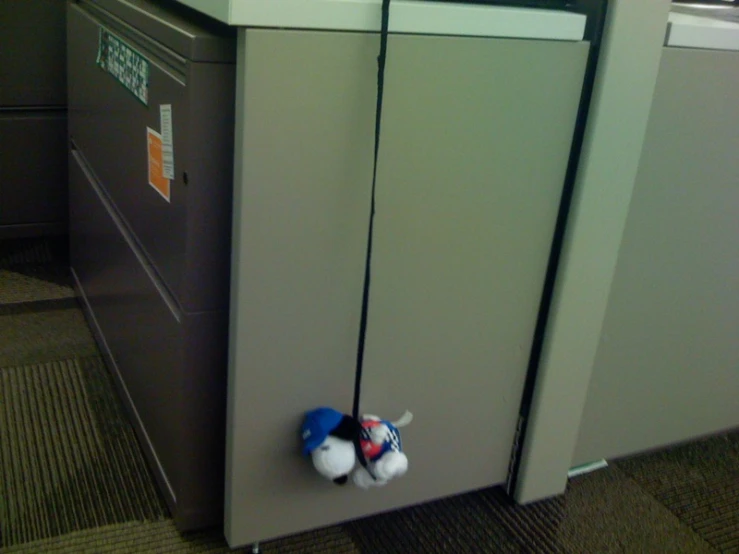 two stuffed animals tied to the top of an office filing cabinet