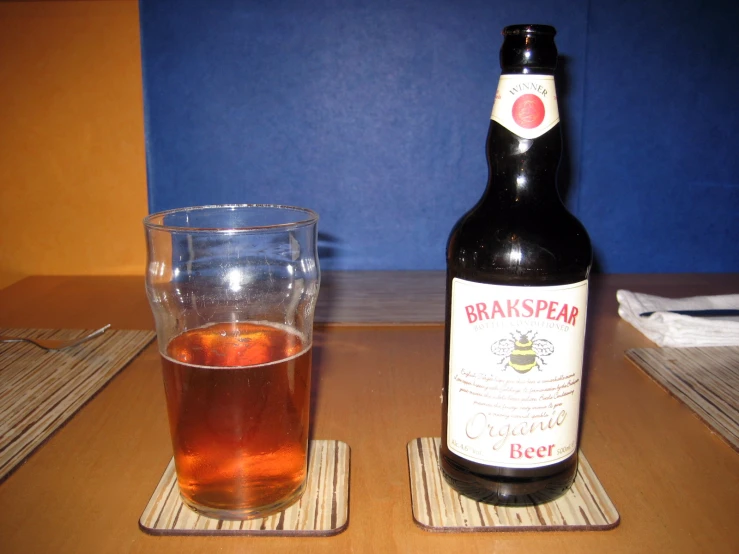 glass and bottle of beverage with small coaster on table