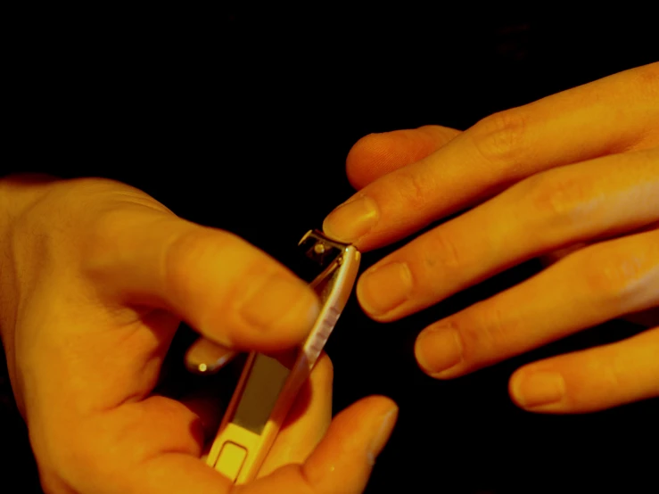 a hand holding a smart phone with a tiny device in their fingertips