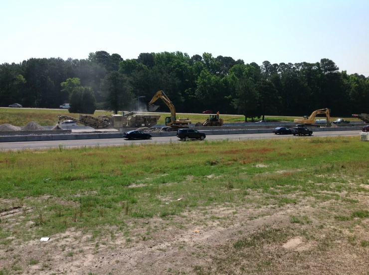 two black cars driving down a road past construction equipment