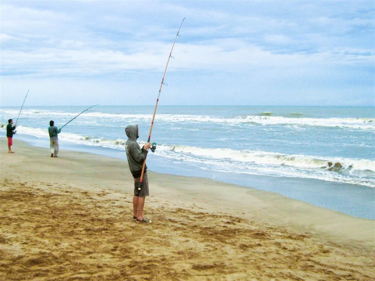 two people on the beach fishing off of a hook