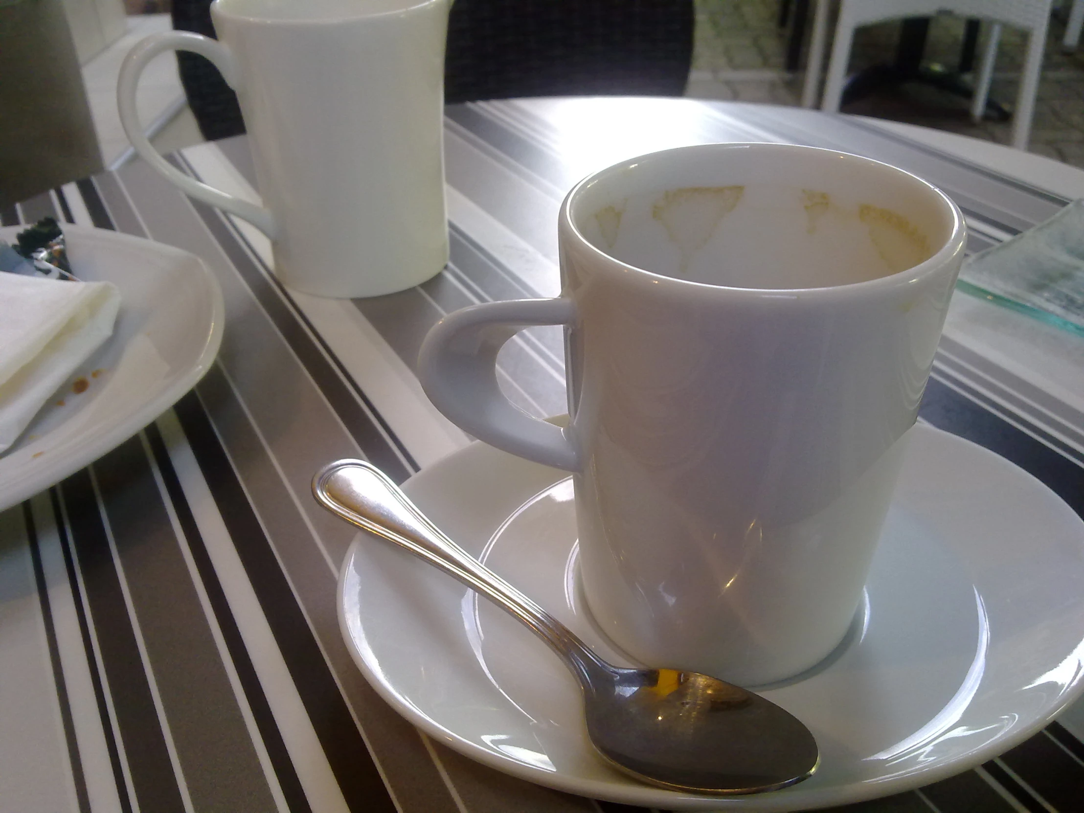 a close up of a cup on a plate with a spoon